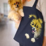 Photo lifestyle : femme portant un spitz et un tote bag artisanal décoré du portrait du chien